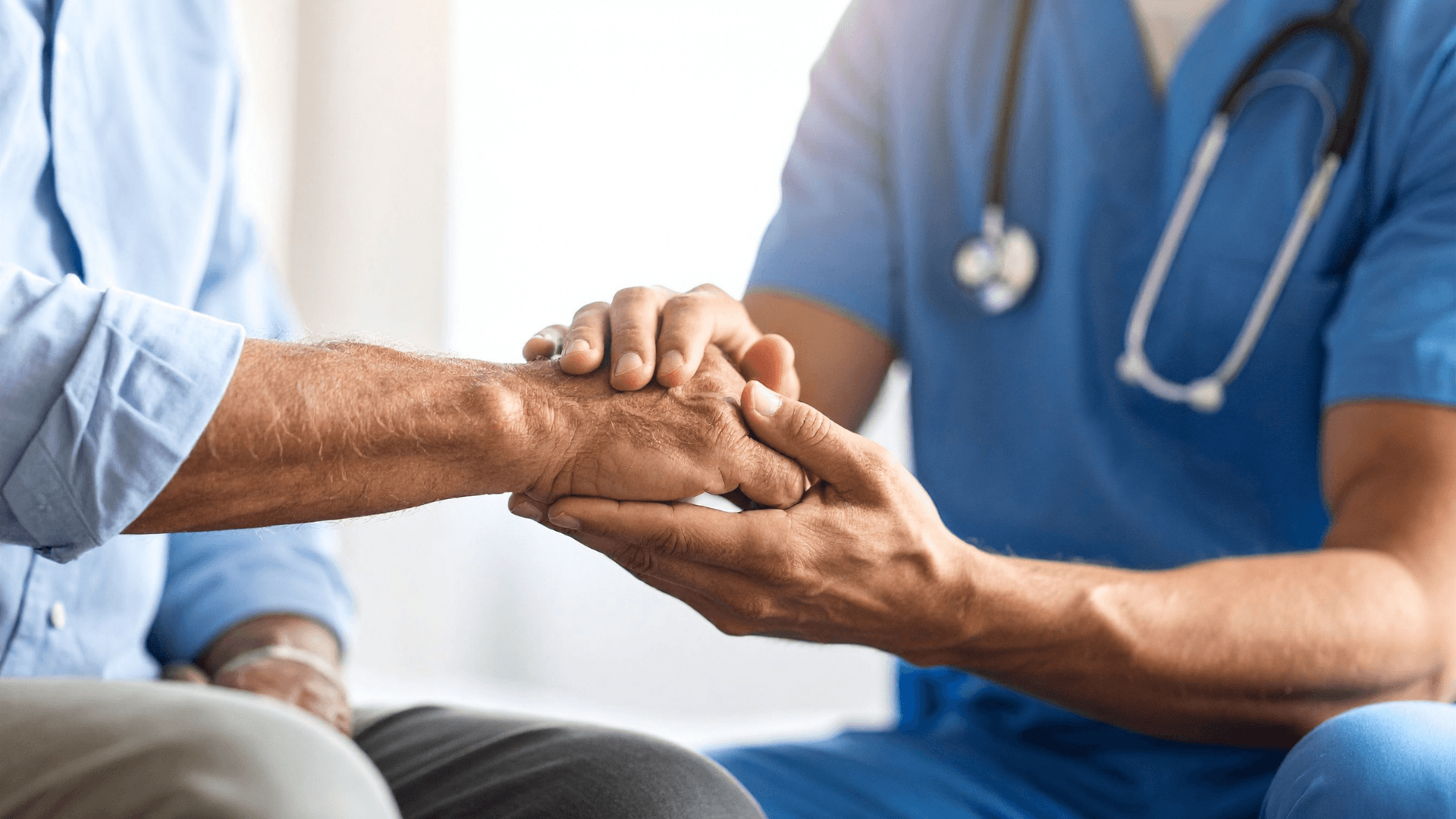 Medical provider wearing blue scrubs gently holding an elderly patient's hand for compassionate care and Social Security Disability support.
