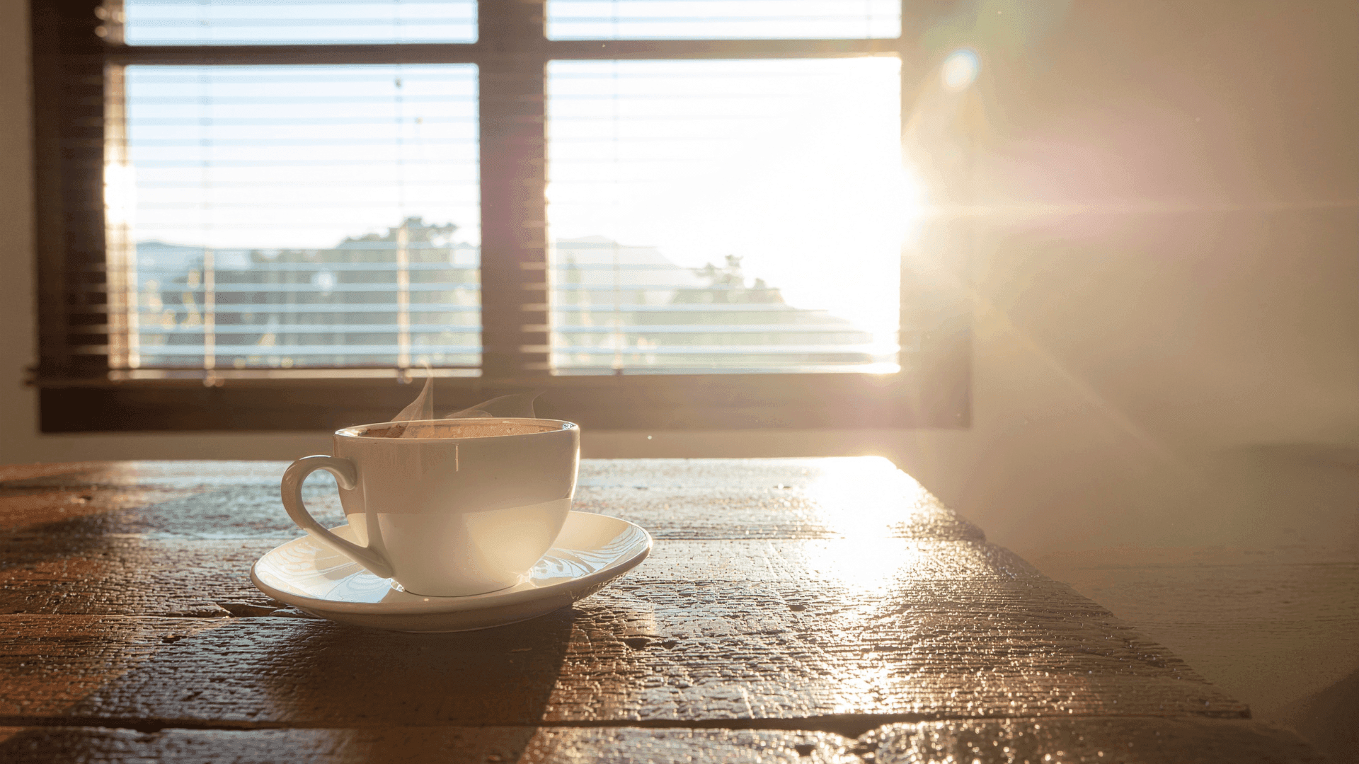 Steaming cup of coffee on a table at sunrise, symbolizing a fresh start after completing a Chapter 13 repayment plan.