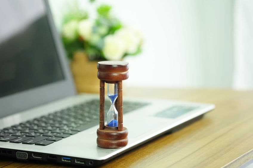 Wooden hourglass on a laptop computer, Managing time and countdown to deadline concept.