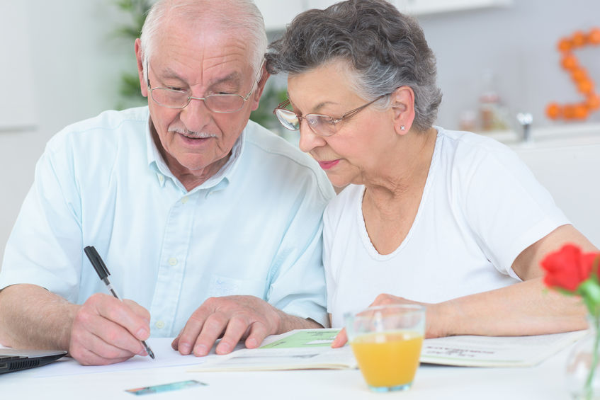 Elderly couple looking at disability list and taking notes