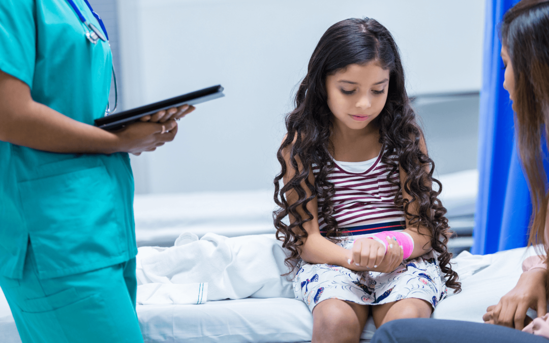 Young girl with an injured wrist sitting beside her parent in a hospital exam room, illustrating a child personal injury claim.