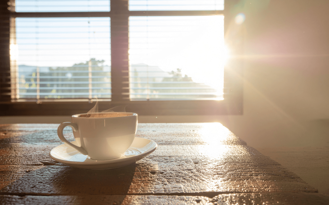 Steaming cup of coffee on a table at sunrise, symbolizing a fresh start after completing a Chapter 13 repayment plan.